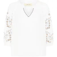 Cream Serini women's blouse with floral embroidery on sleeves and studded V-neckline.