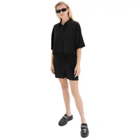 Black women's drawstring shorts, loose fit, paired with matching shirt, worn by model with sunglasses and black shoes.
