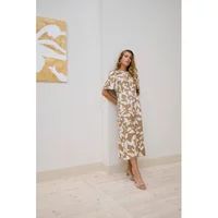 Beige and white floral-patterned midi dress with short sleeves and a relaxed fit, worn by a woman standing indoors.