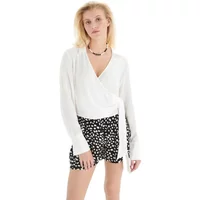 Black and white polka dot linen blend shorts with elastic waistband, worn by a model in a white wrap top.
