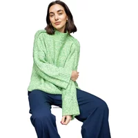 Green knit sweater with wide sleeves paired with navy wide-leg trousers.