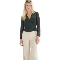 Black polka dot wrap blouse with long sleeves and V-neck, worn by a model with beige pants.