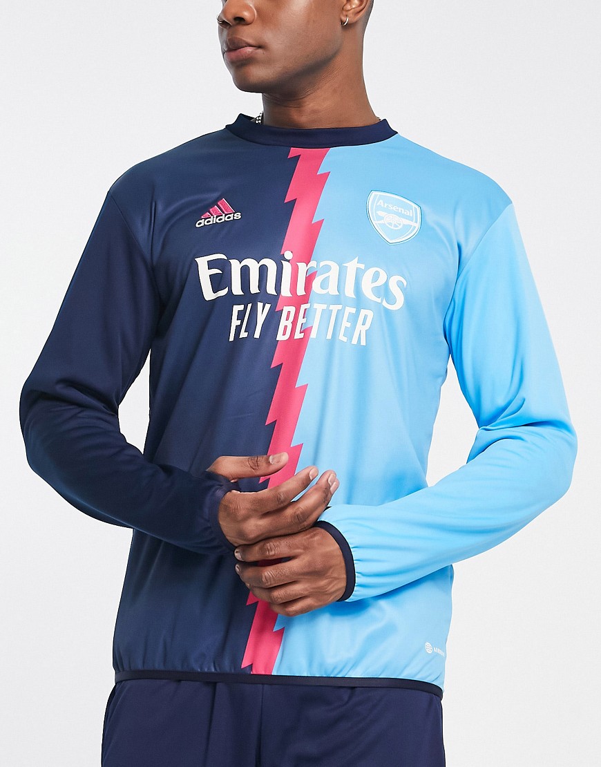 Navy and sky blue Arsenal Pre Match Warm Top featuring a bold lightning bolt design, Adidas logo, and "Emirates Fly Better" branding across the chest.