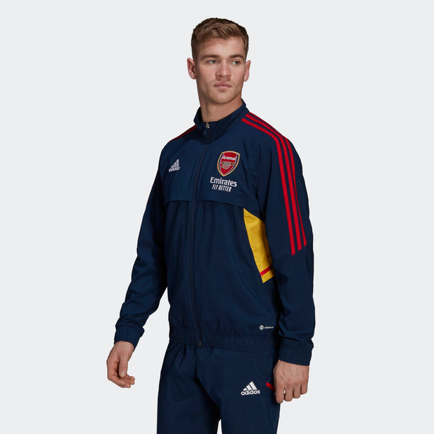 Navy blue Adidas track top featuring red and yellow accents, Arsenal crest on the chest, zip-up front, and three stripes on the shoulders, designed for men's athletic wear.