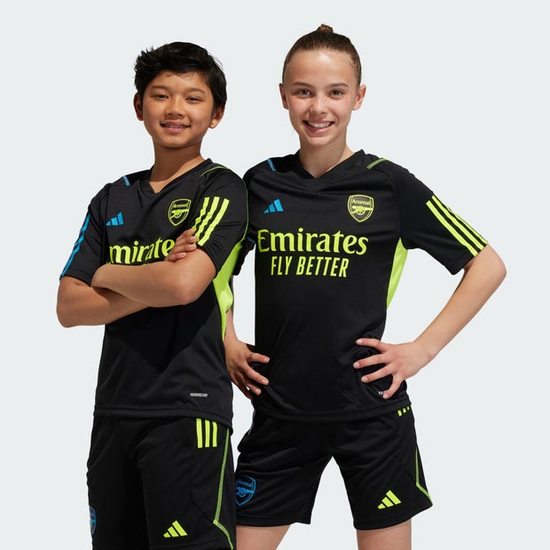 Black Arsenal Adidas training jersey for kids featuring neon green accents, short sleeves, and the Emirates logo prominently displayed on the front.
