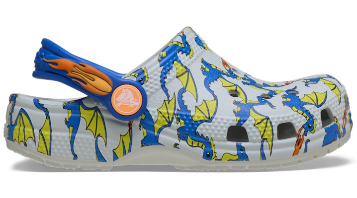 White Crocs clogs featuring a colorful dragon graphic in blue and yellow, with an orange heel strap and ventilation holes for breathability.