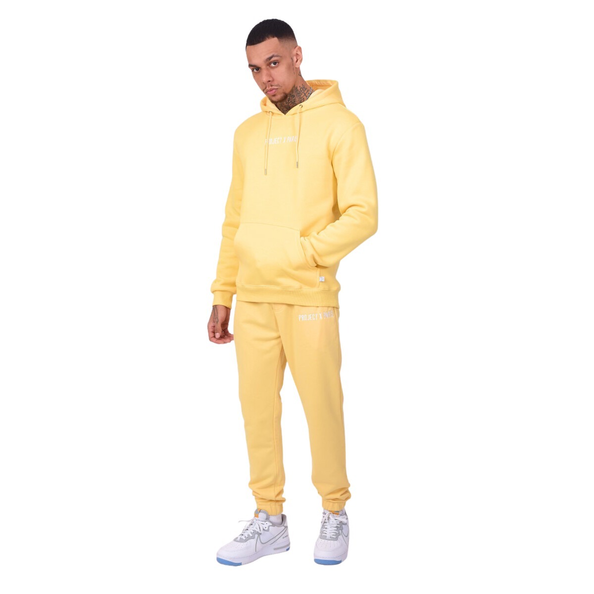 Yellow embroidered jogging pants featuring a subtle logo, made from soft material, paired with a matching hoodie and white sneakers.