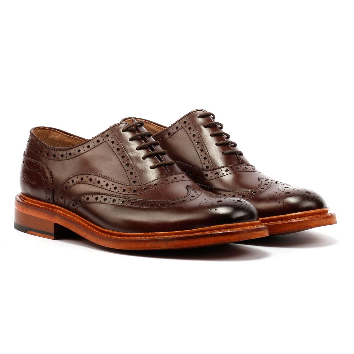 Brown leather lace-up brogue shoes featuring intricate perforated detailing, a rounded toe, and a contrasting tan sole, embodying classic men's footwear style.