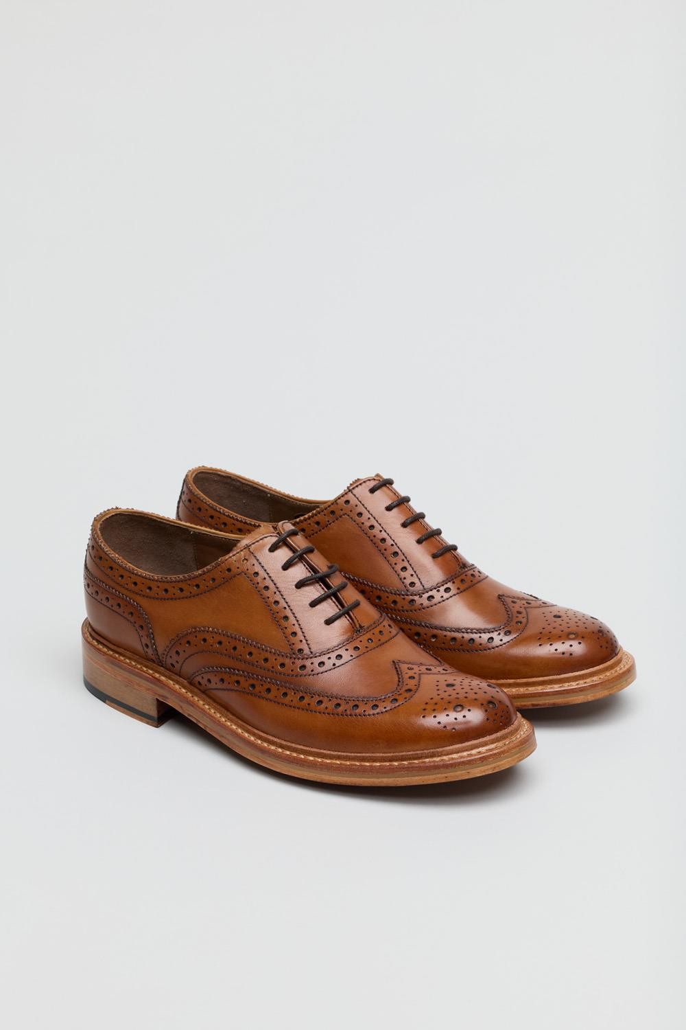 Tan leather lace-up brogue shoes featuring decorative perforations, a rounded toe, and a sturdy wooden sole, designed for a classic and stylish look.