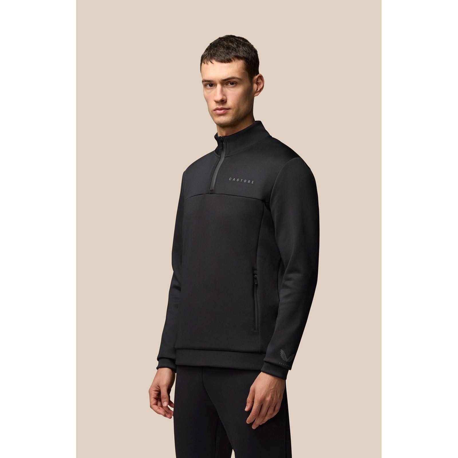 Black 1/4 zip sweatshirt made of polyester, featuring a high collar, zippered front pocket, and subtle logo on the chest, worn by a model against a neutral background.