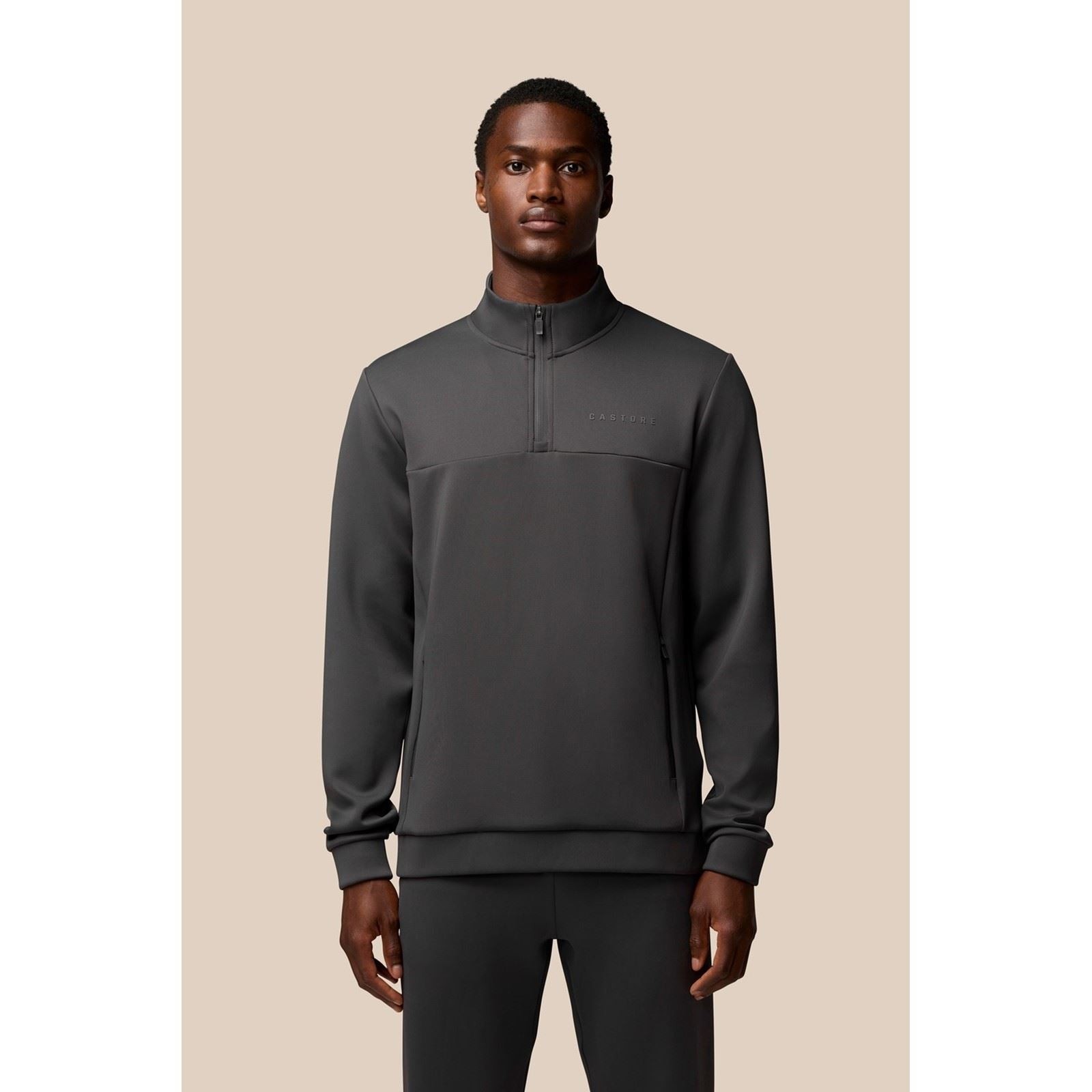 Grey polyester sweatshirt featuring a 1/4 zip, high collar, and subtle branding on the chest, designed for men with a sleek, athletic fit.