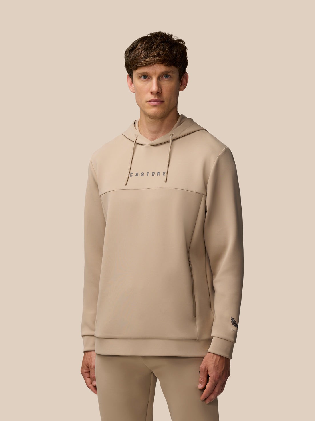 Brown polyester hooded sweatshirt featuring a front pocket, drawstring hood, and "CASTORE" logo on the chest, designed for a sleek, athletic look.