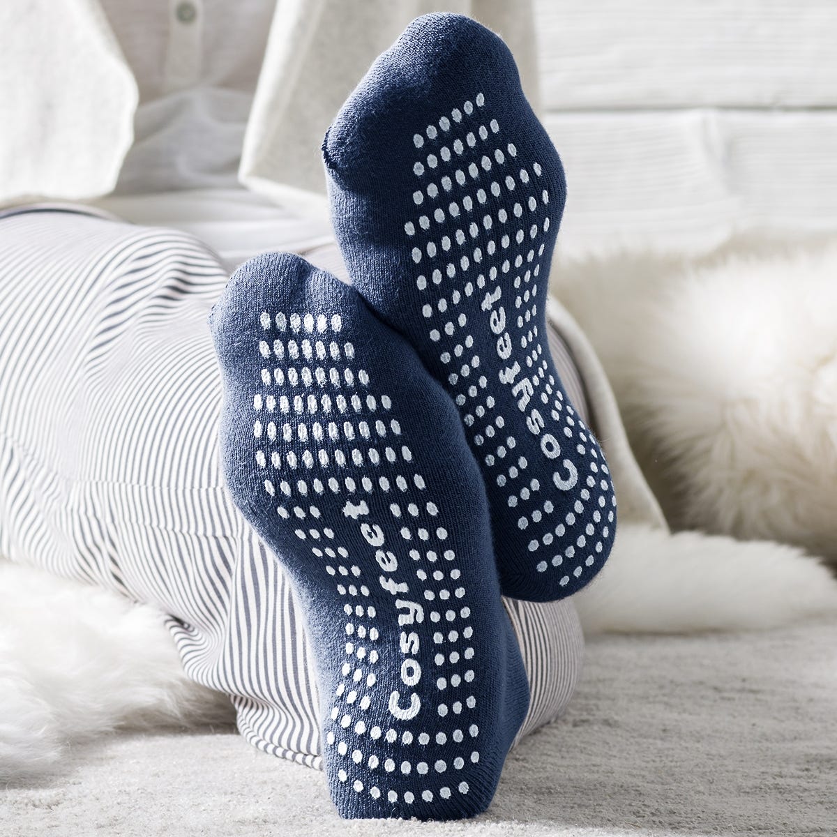 Navy blue, soft fabric socks featuring white gripped dots on the soles and "Cosyfeet" branding, designed for comfort and slip resistance.