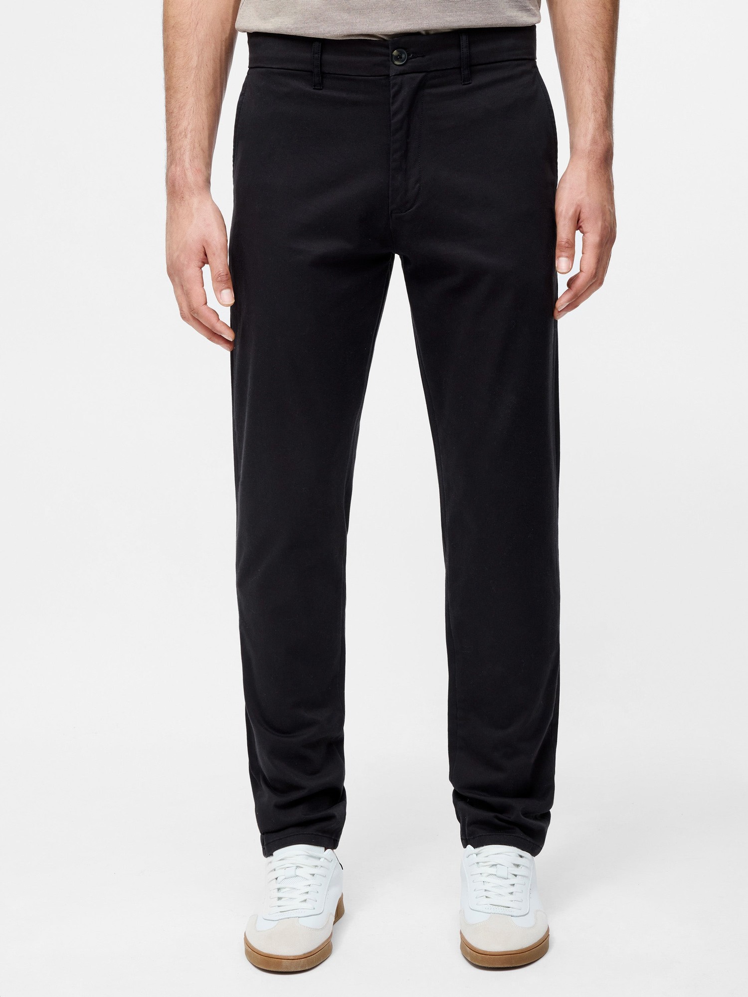 Black cotton stretch chinos with a regular fit, featuring a button and zip fly, side pockets, and a sleek design, paired with white sneakers.
