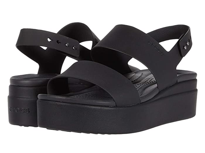 Black low wedge sandals featuring two wide straps, a cushioned footbed, and a thick platform sole, designed by Crocs for comfort and style.