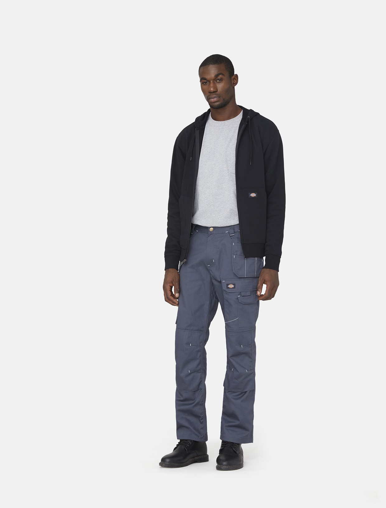 Men's grey outdoor trousers made of durable polyester, featuring multiple pockets and a relaxed fit, paired with a black hoodie and grey t-shirt.