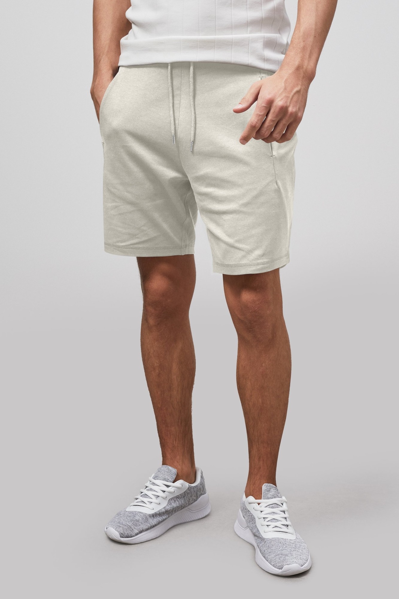 Men's white essential drawstring jersey shorts in UK XL by Enorsia, featuring an elastic waistband, side pockets, and a relaxed fit, paired with grey athletic shoes.