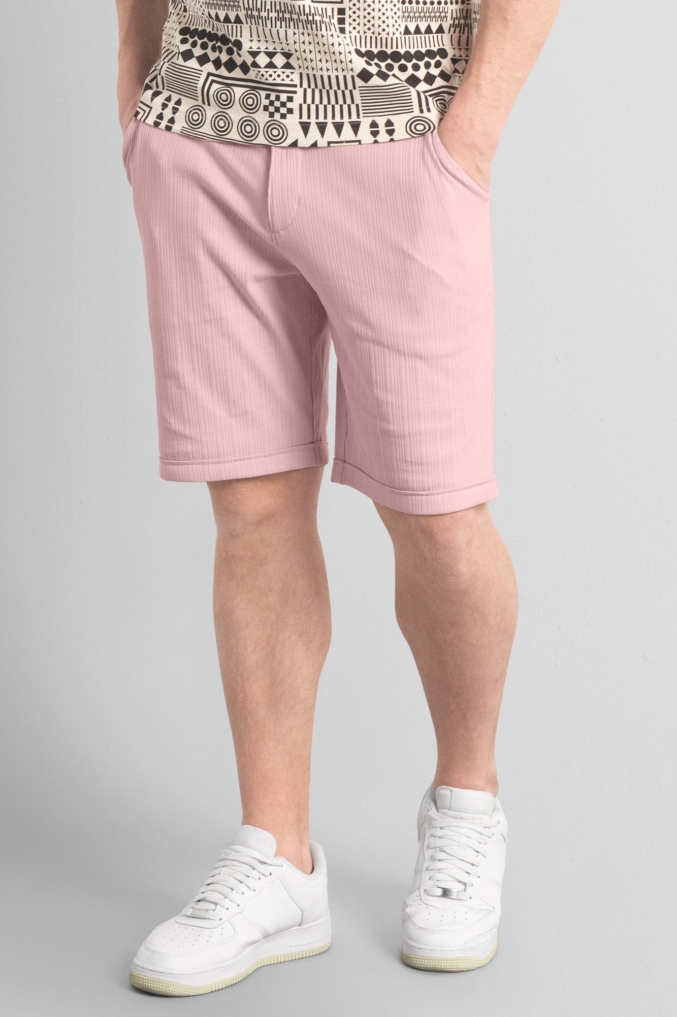 Pink smart jersey chino shorts for men, featuring a relaxed fit, side pockets, and a smooth fabric texture, paired with a patterned top and white sneakers.