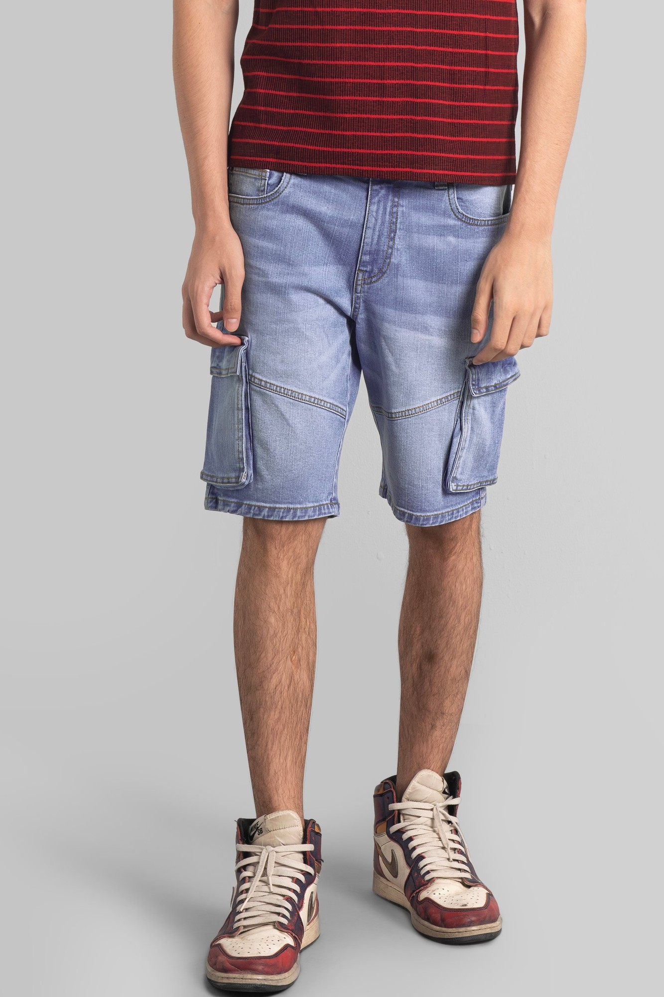 Sky blue denim cargo shorts featuring multiple side pockets, a relaxed fit, and a UK size 38, paired with a red striped shirt and sneakers.