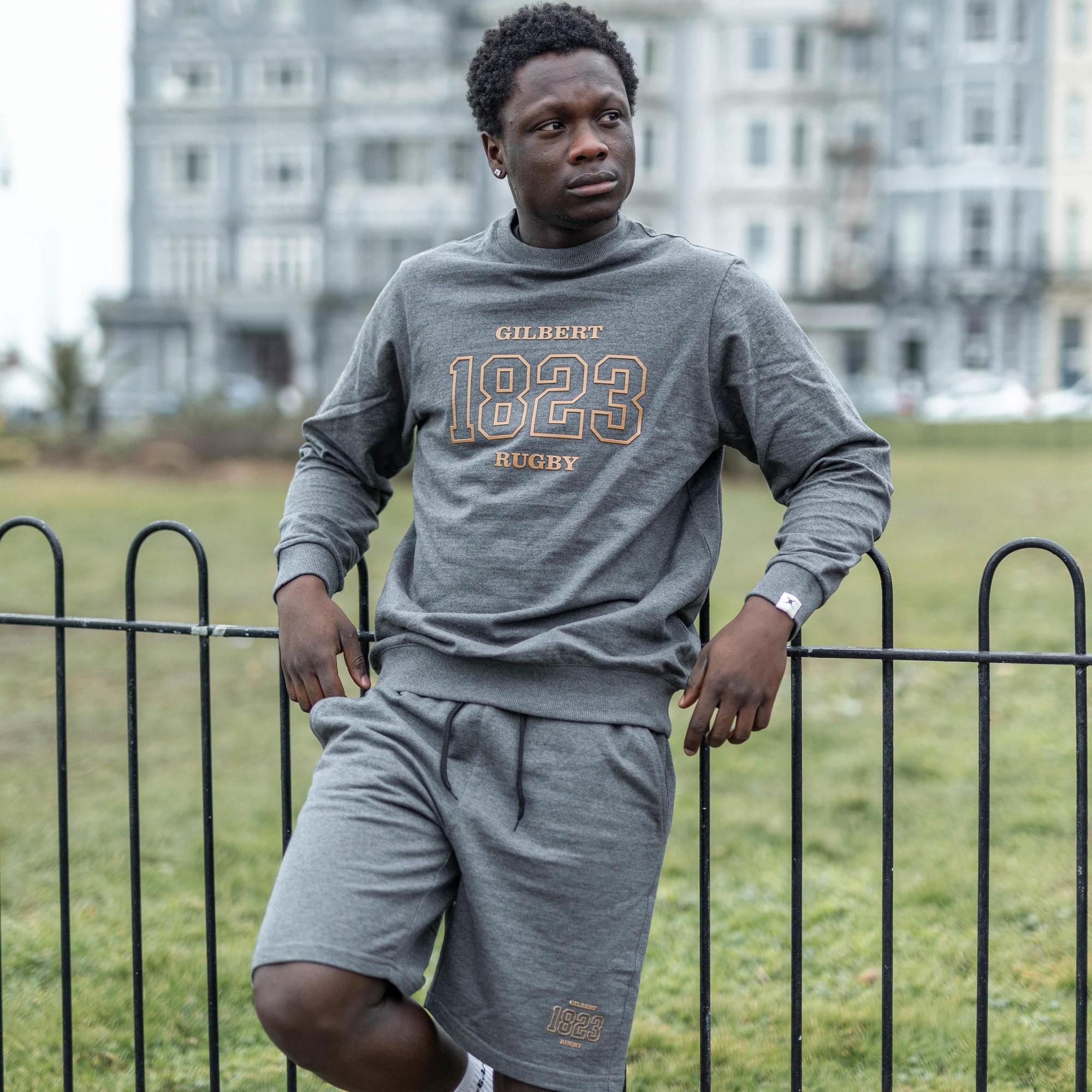 Gray leisure shorts made of soft fabric, featuring an elastic waistband, side pockets, and a subtle embroidered "1823" logo in gold on the left leg.