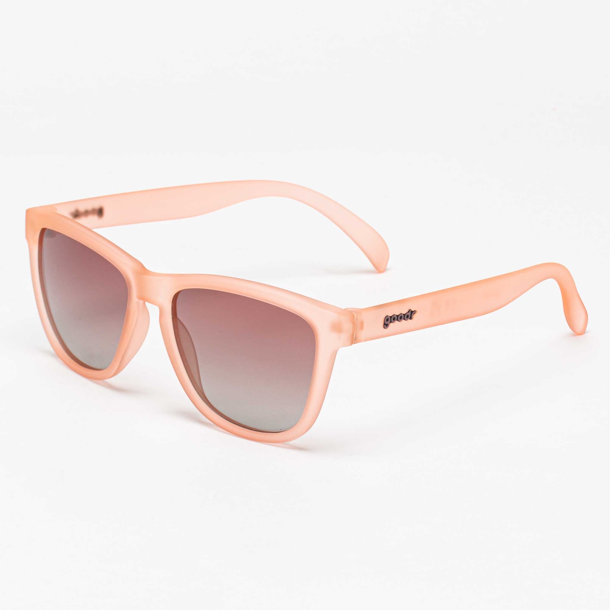 Light pink, translucent sunglasses with a square frame and gradient lenses, featuring the Goodr logo on the arms.