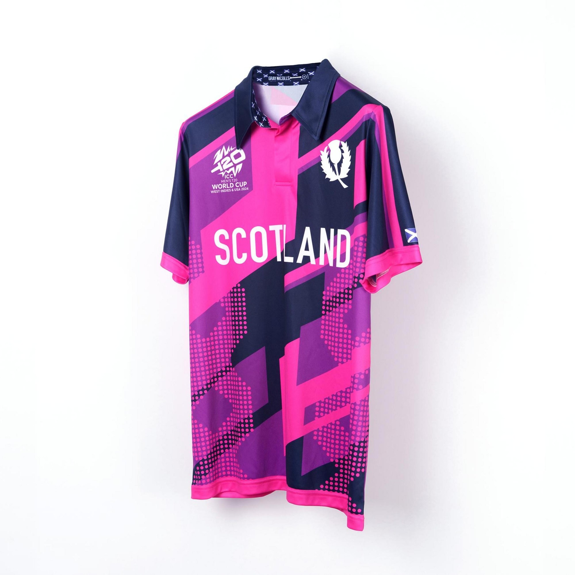 Junior short sleeve cricket shirt in vibrant pink and navy, featuring Scotland branding, a collar, and geometric patterns, designed for the T20 World Cup 2024.