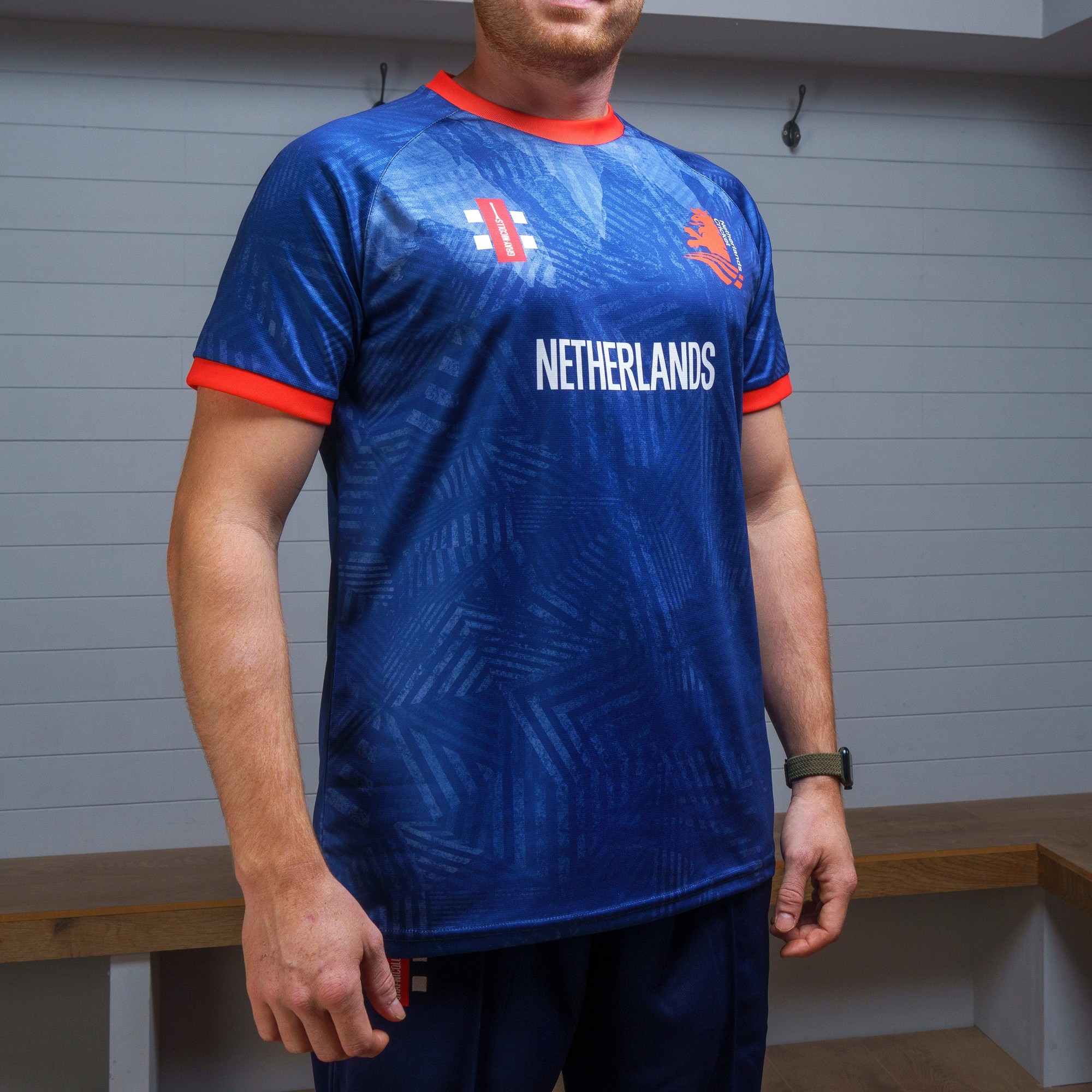 Blue training shirt featuring the Netherlands logo, red accents on the collar and sleeves, and a textured pattern throughout the fabric, made by Gray-Nicolls.