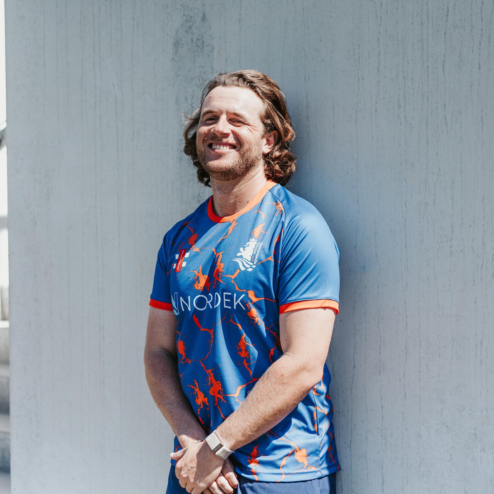 Men's short sleeve training shirt in blue with orange accents, featuring a dynamic design and the Gray-Nicolls logo, suitable for T20 cricket practice.