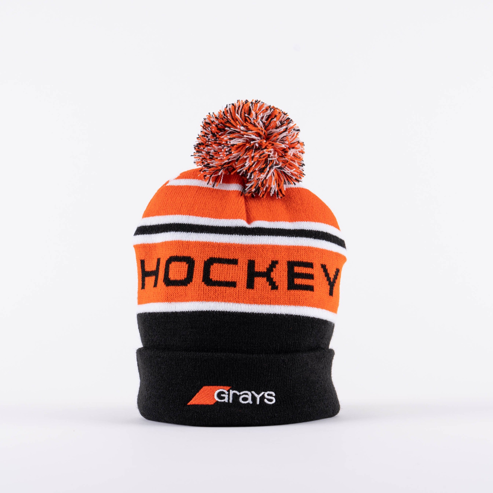 Black bobble hat featuring an orange and white striped design, bold "HOCKEY" text, and a colorful pom-pom on top, made from soft knit material by Grays Hockey.