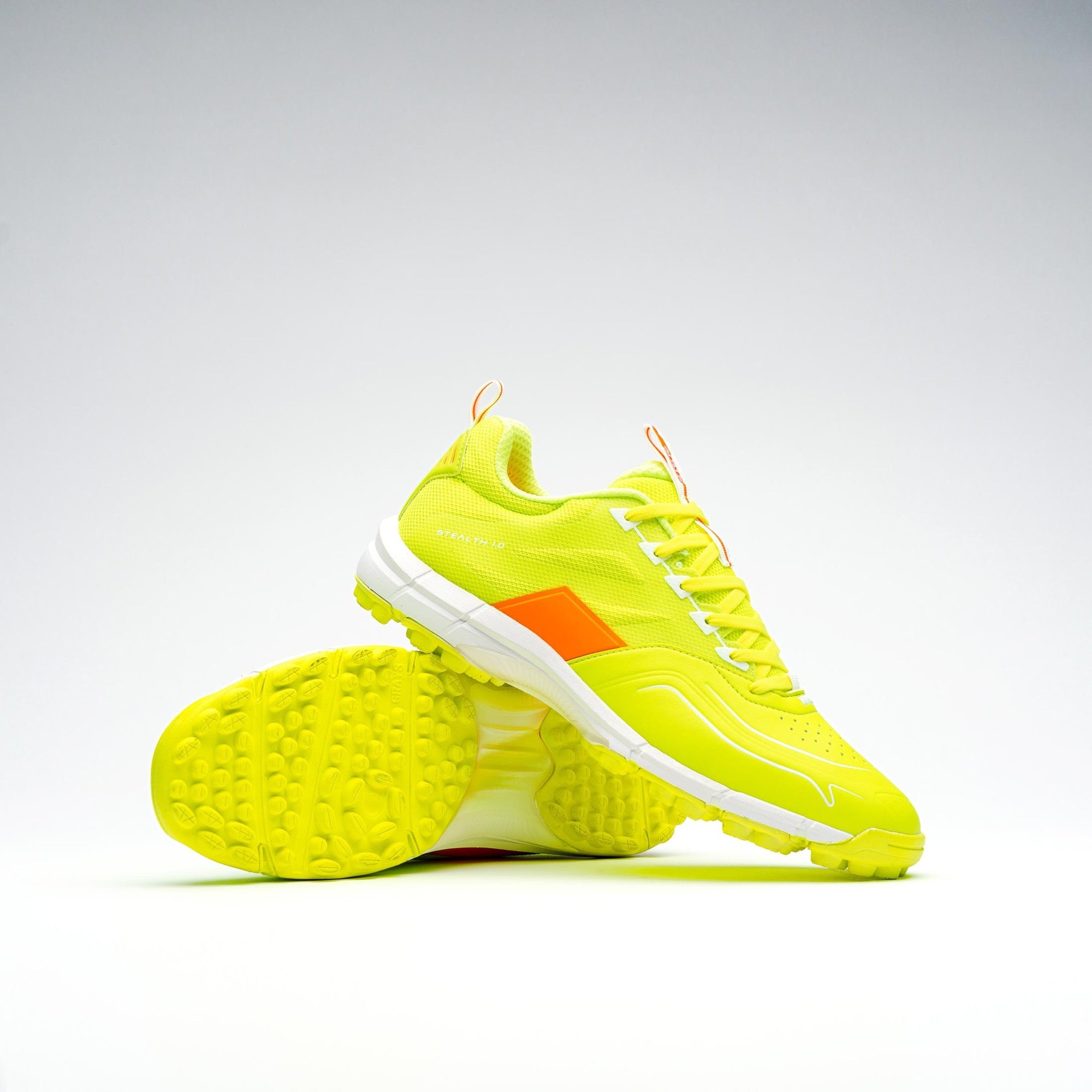Bright fluo yellow Grays Stealth shoes feature a textured upper, white accents, and a distinctive orange logo, with a durable outsole designed for traction on the field.