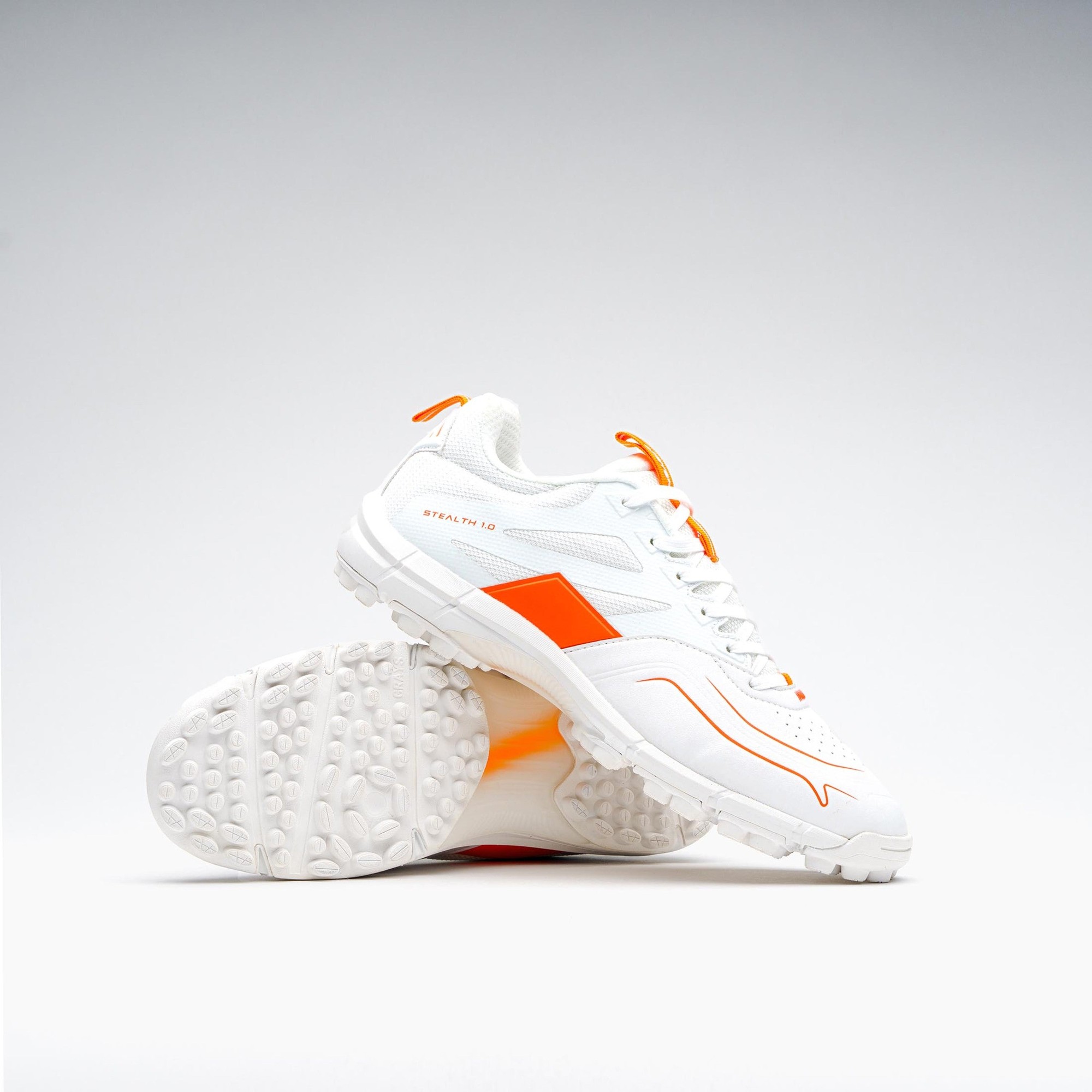 White Grays Stealth shoes featuring orange accents, a textured rubber sole, and a lightweight design, ideal for hockey performance.
