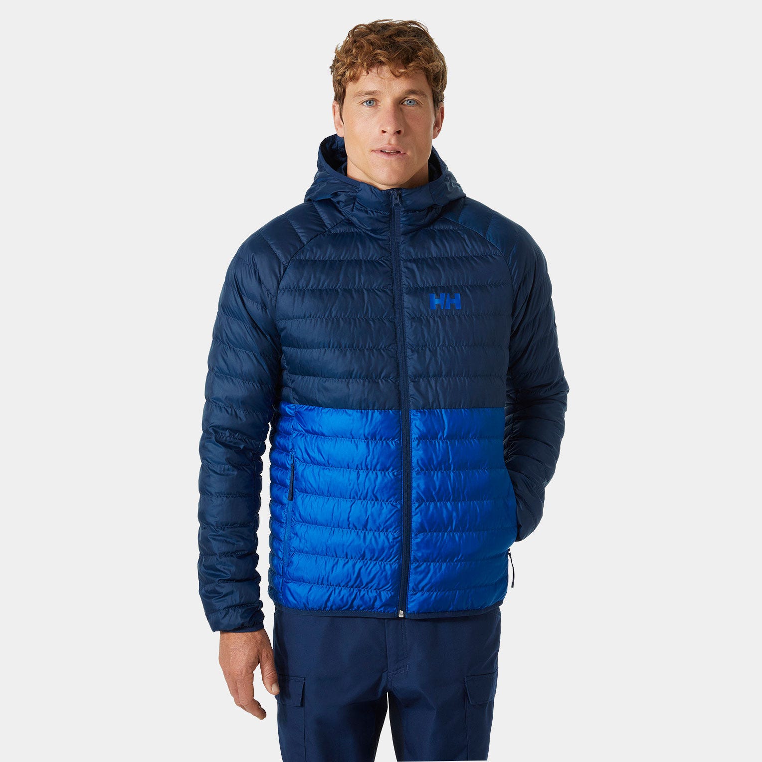 Insulated hooded puffer jacket in navy blue and bright blue, featuring a zip front, quilted design, and Helly Hansen logo on the chest.