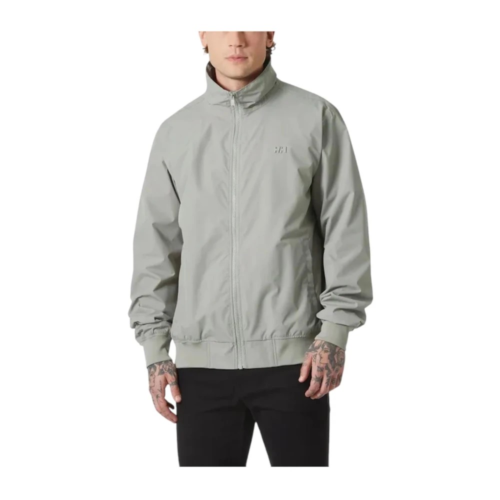 Light grey waterproof jacket by Helly Hansen, featuring a zip front, high collar, and elastic cuffs, designed for comfort and protection against the elements.