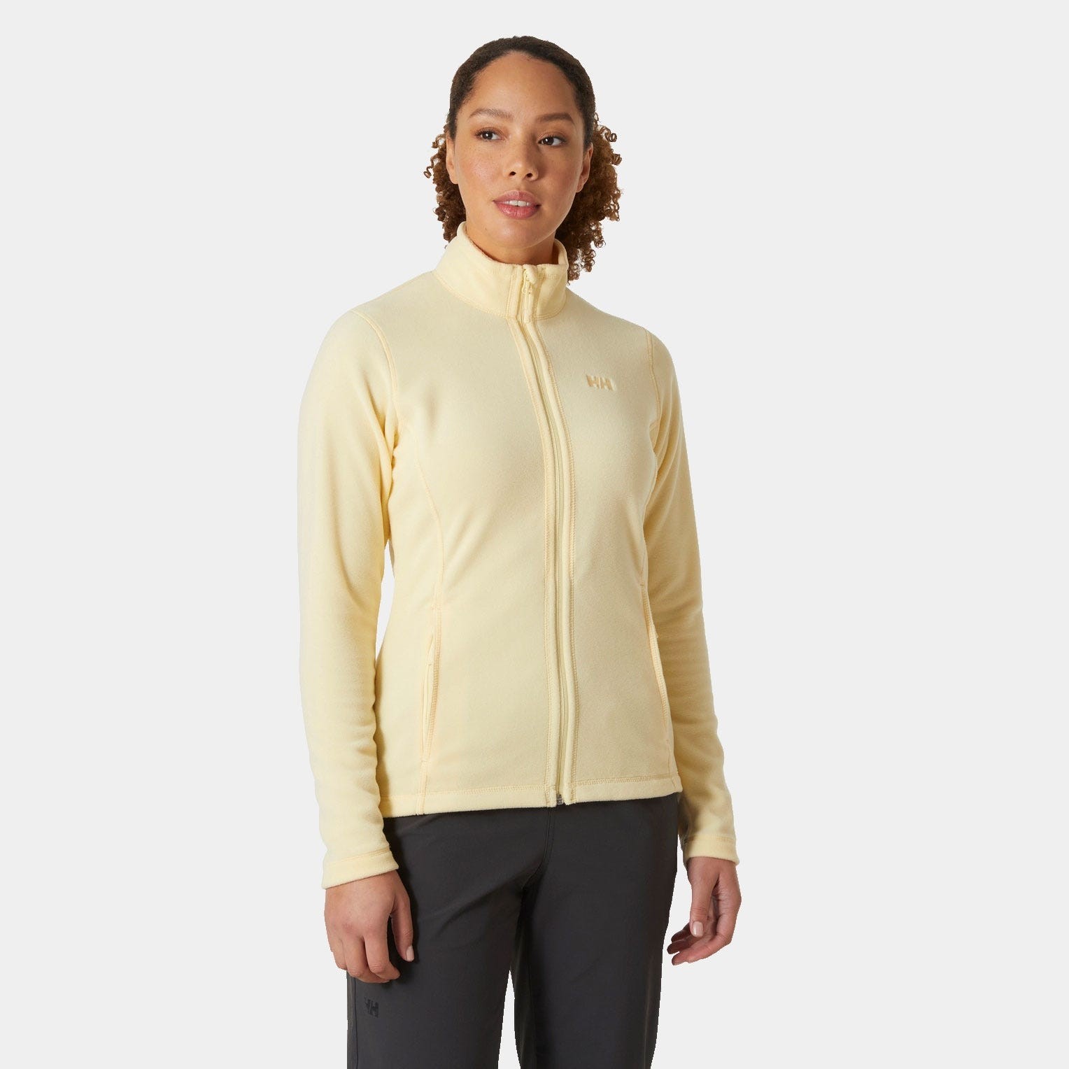 Light yellow women's fleece jacket featuring a high collar, full zip front, and subtle Helly Hansen logo on the chest, perfect for layering in cooler weather.