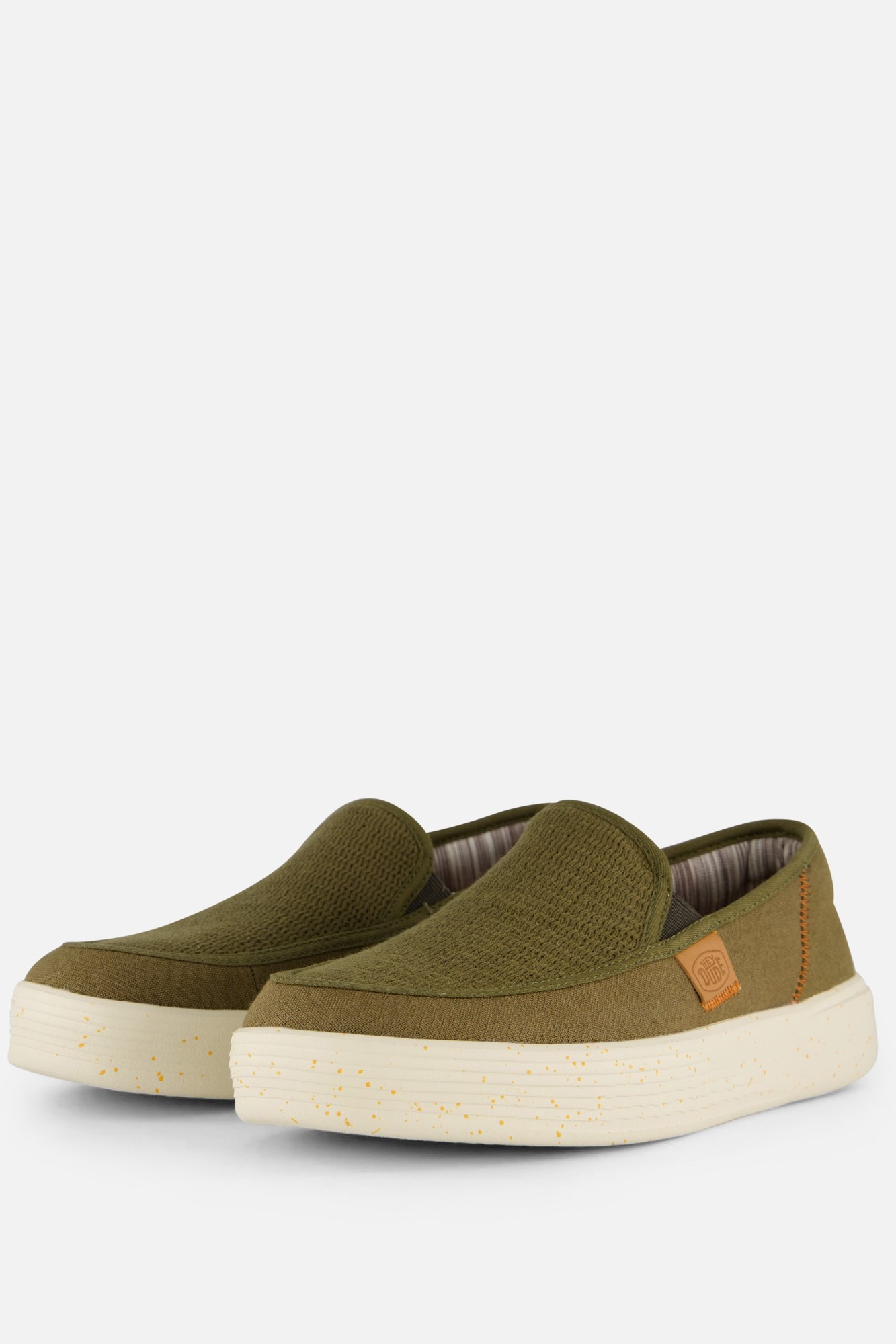 Olive green slip-on shoe with a textured upper, featuring a white speckled sole and a small tan logo patch on the side.