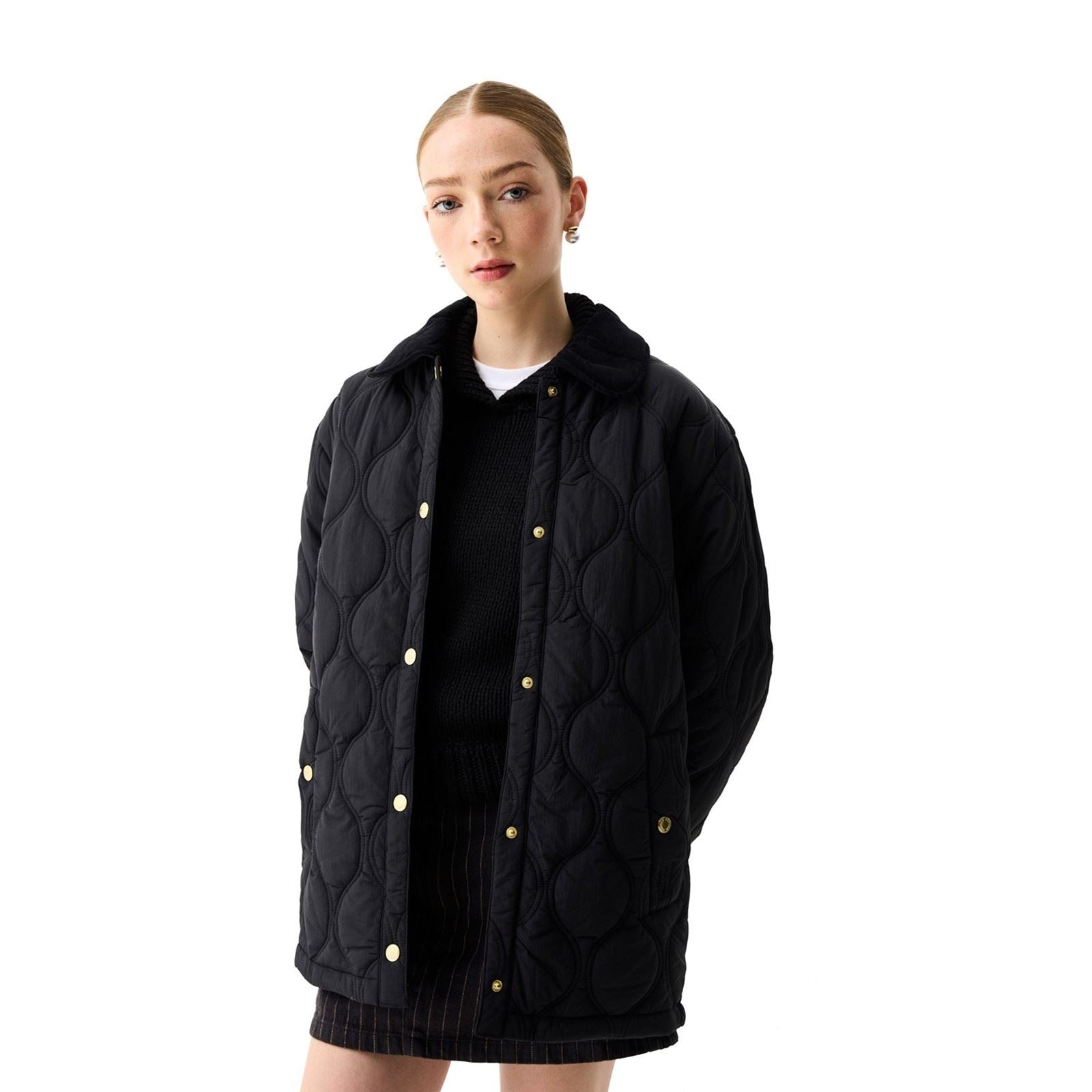 Black quilted jacket by Hunter featuring a button-up front, a soft collar, and a relaxed fit, worn over a black sweater and skirt.