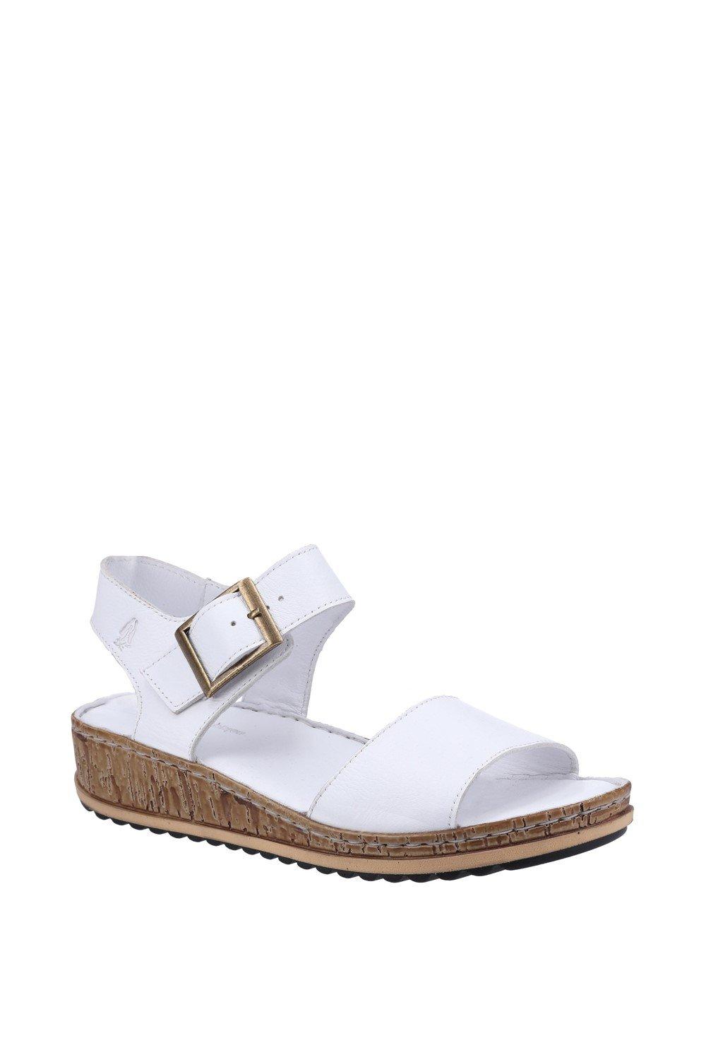 White leather 'Ellie' sandal by Hush Puppies featuring a wide strap, adjustable buckle, and a cork-wrapped wedge sole for comfort and style.