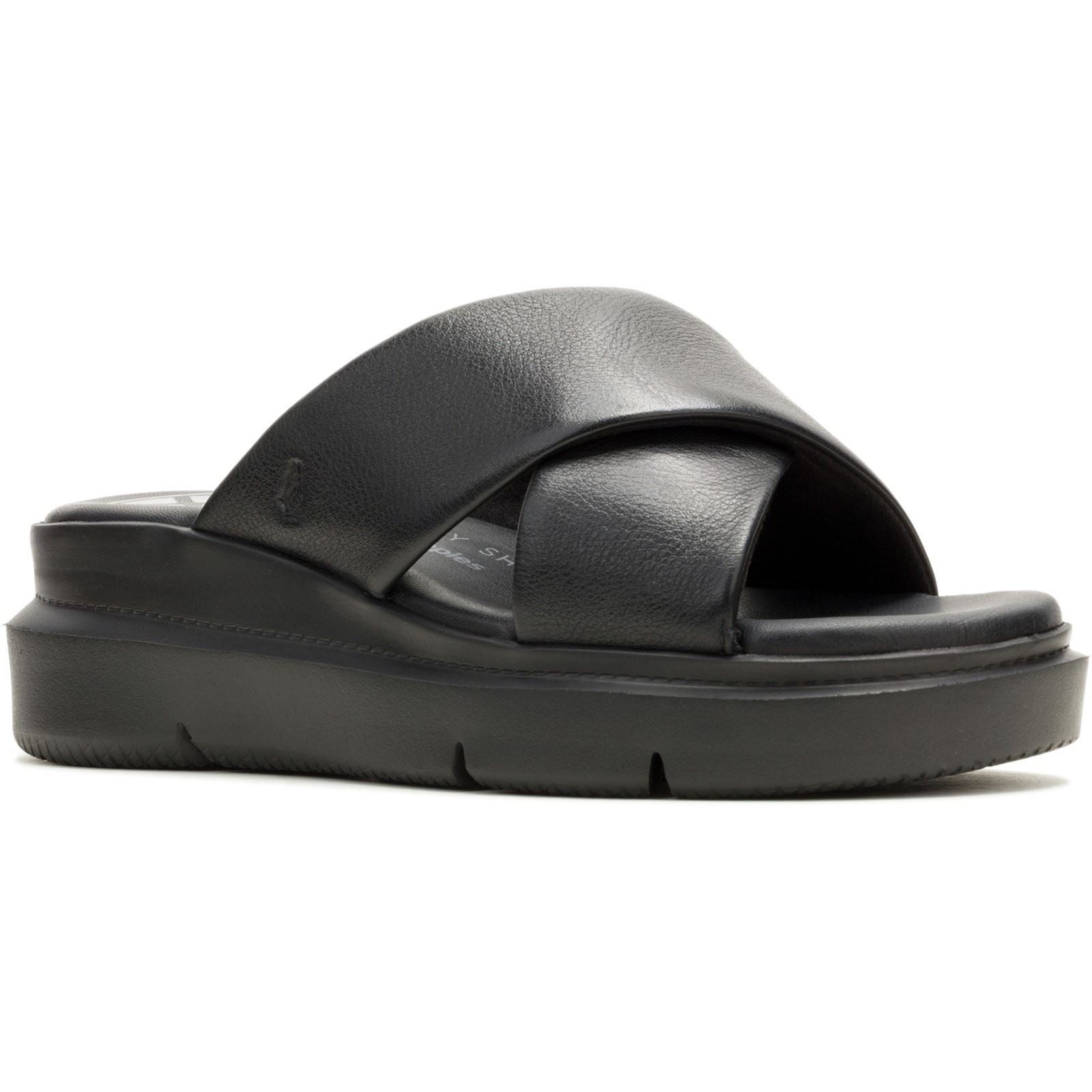 Black leather crossover slide sandals with a cushioned footbed and a thick, textured sole, featuring a sleek and modern design by Hush Puppies.