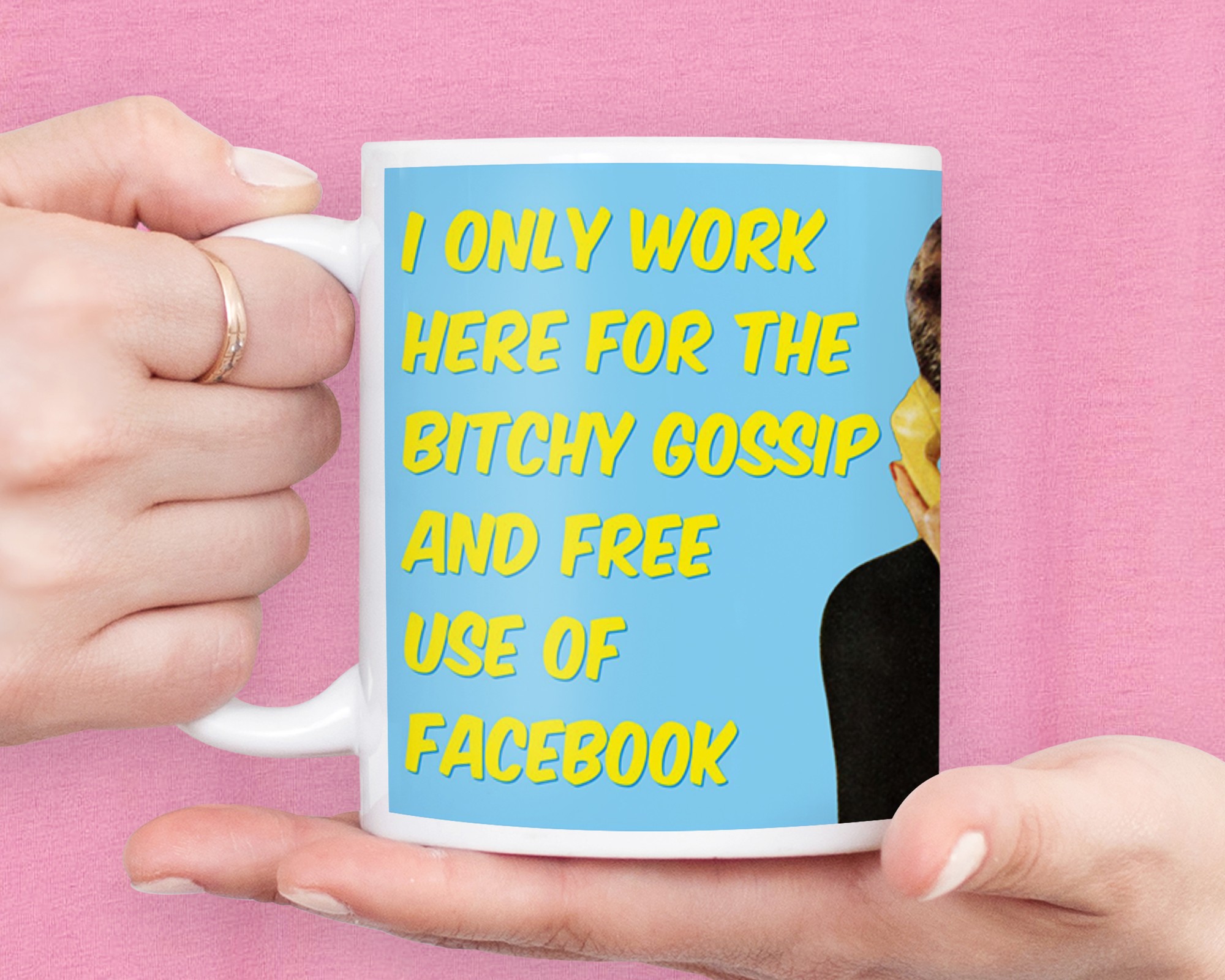 White ceramic mug featuring bold yellow text that reads "I ONLY WORK HERE FOR THE BITCHY GOSSIP AND FREE USE OF FACEBOOK" on a light blue background, held by a hand.