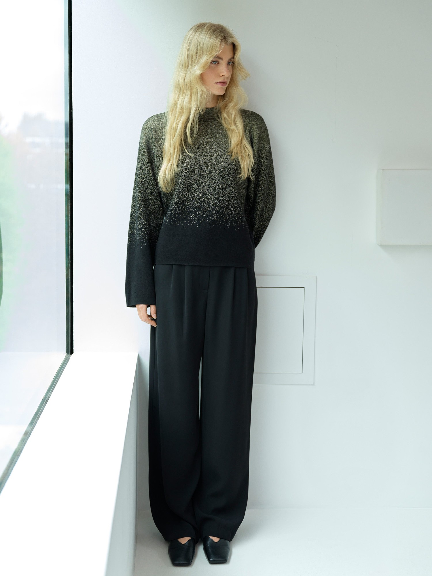 Glitter ombre jumper in black and gold, featuring a relaxed fit, long sleeves, and a soft, textured material, paired with loose black trousers and sleek black shoes.