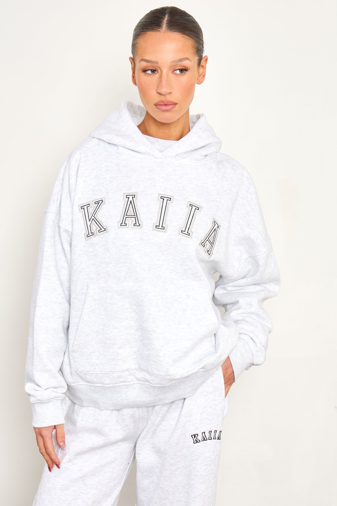 Light grey marl oversized hoodie featuring a chainstitch slogan "KAIIA" in bold lettering, made from soft material, with a spacious hood and relaxed fit.