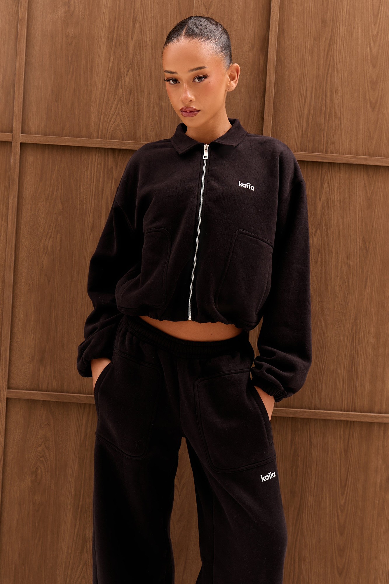 Black zip-through sweatshirt made from soft material, featuring a chrome logo on the chest and pocket details, styled with relaxed fit and dropped shoulders.