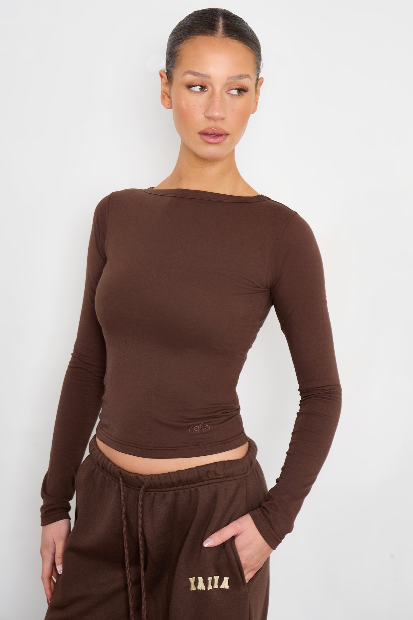 Bitter chocolate long sleeve top made of cotton, featuring a slash neck design and a fitted silhouette, paired with matching casual pants.