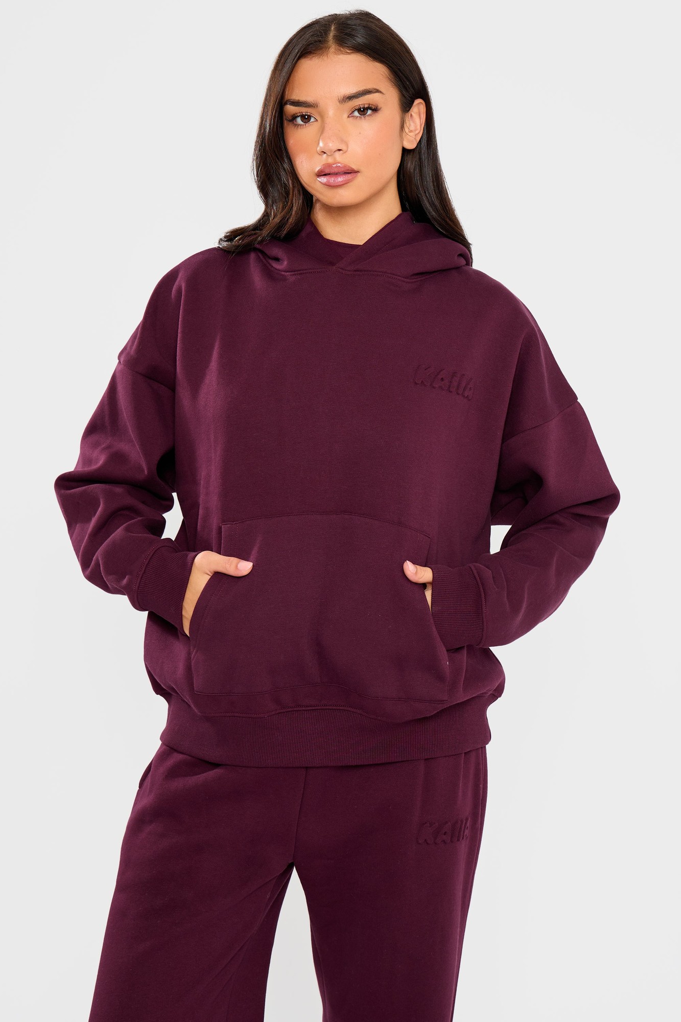 Oversized hoodie in deep merlot burgundy featuring an embossed bubble logo, soft material, and a front pocket, styled with a relaxed fit.