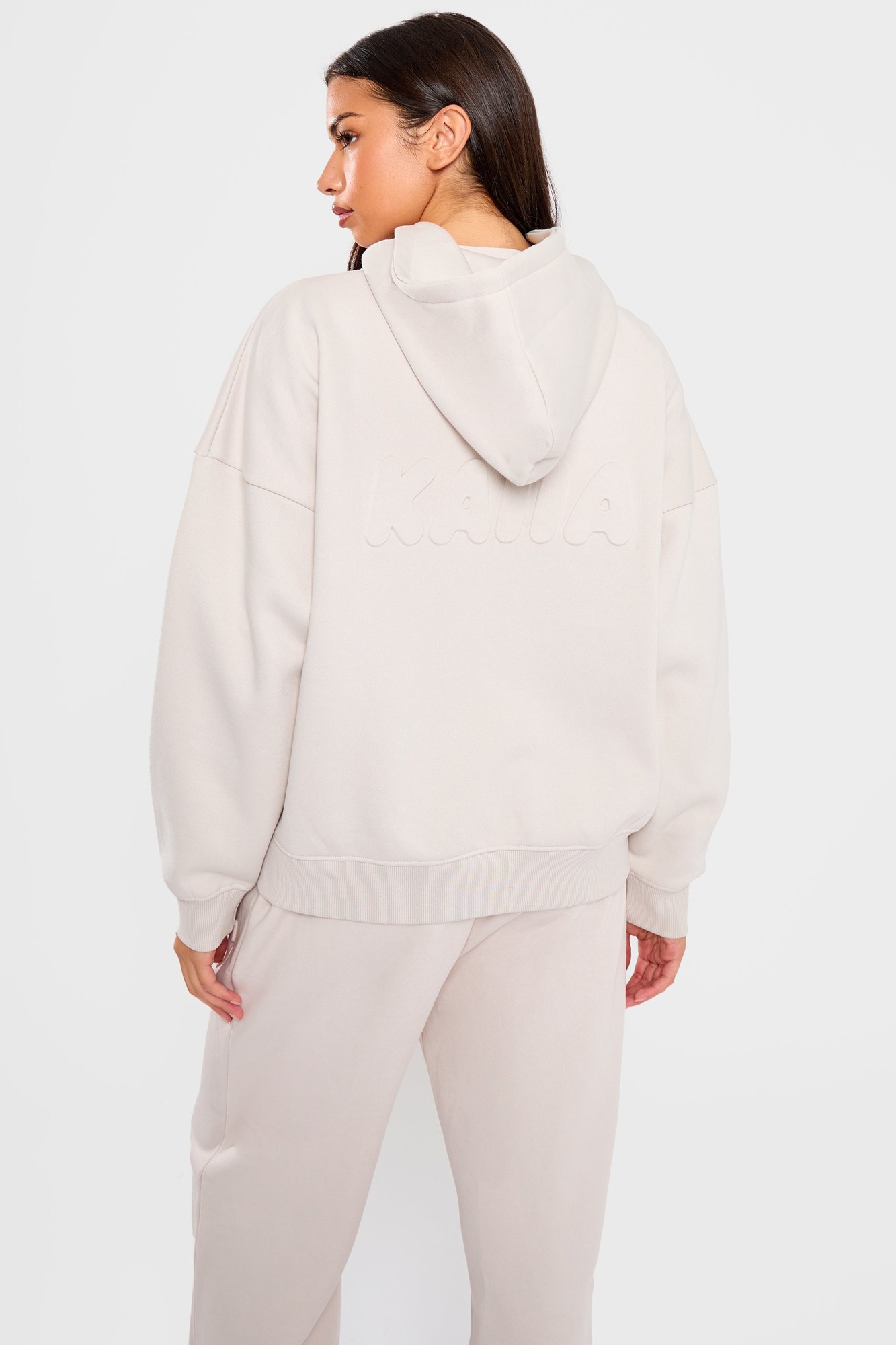 Oversized oyster-colored hoodie featuring an embossed bubble logo on the back, made from soft material with a relaxed fit and a drawstring hood.