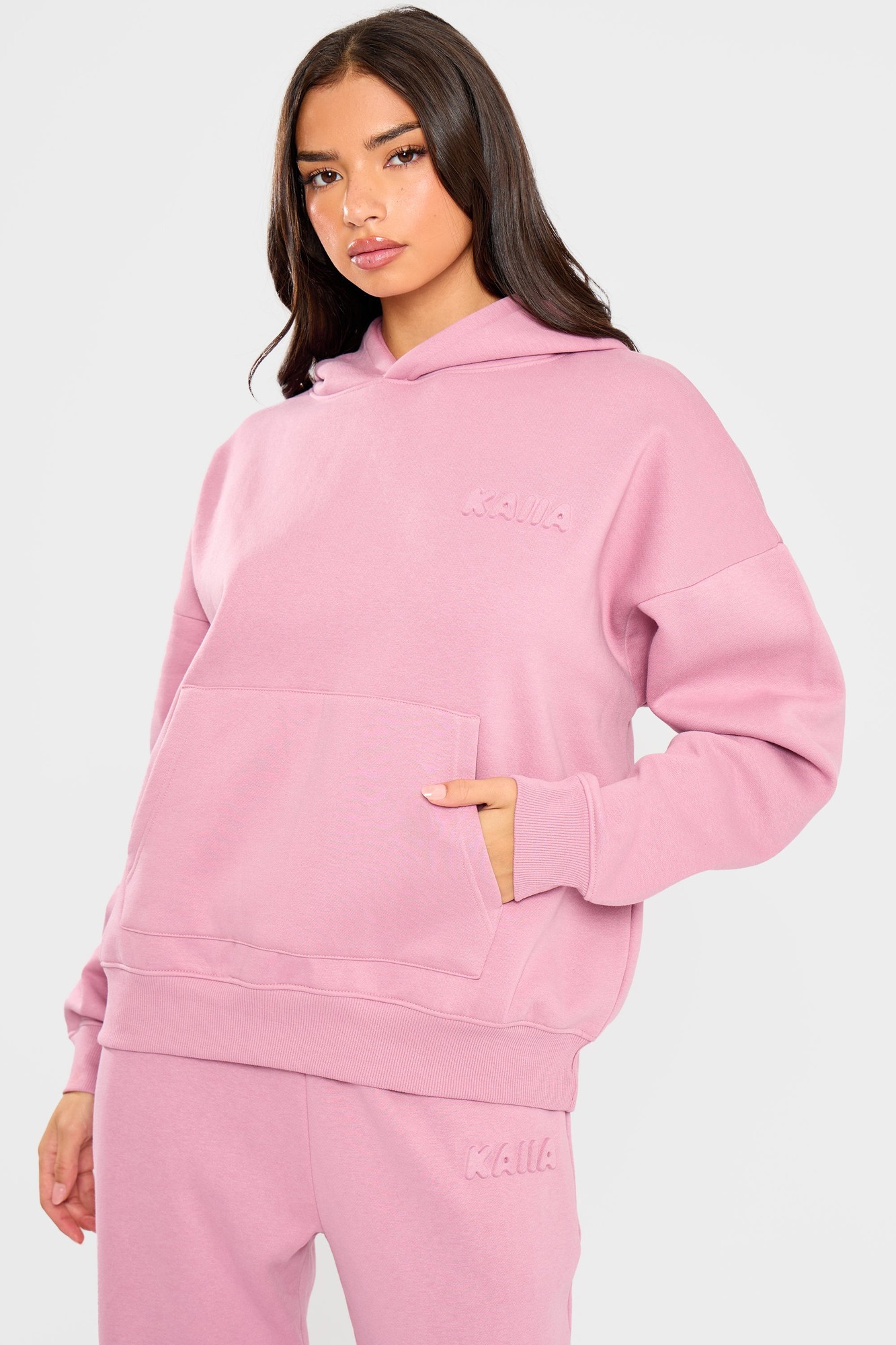 Oversized hoodie in petal pink with an embossed "Kaiia" logo on the chest, featuring a front pocket and a cozy hood.