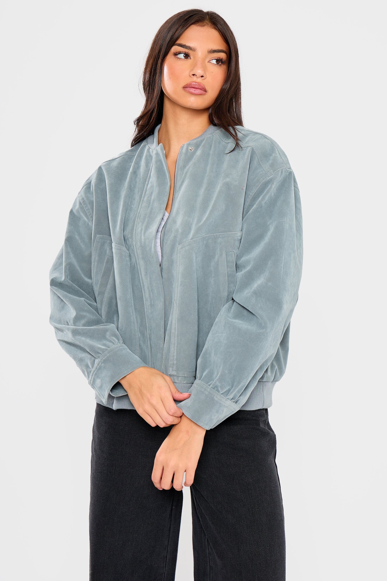 Baby blue faux suede bomber jacket featuring a relaxed fit, front zip closure, and ribbed cuffs, styled with a model wearing a simple top and dark jeans.