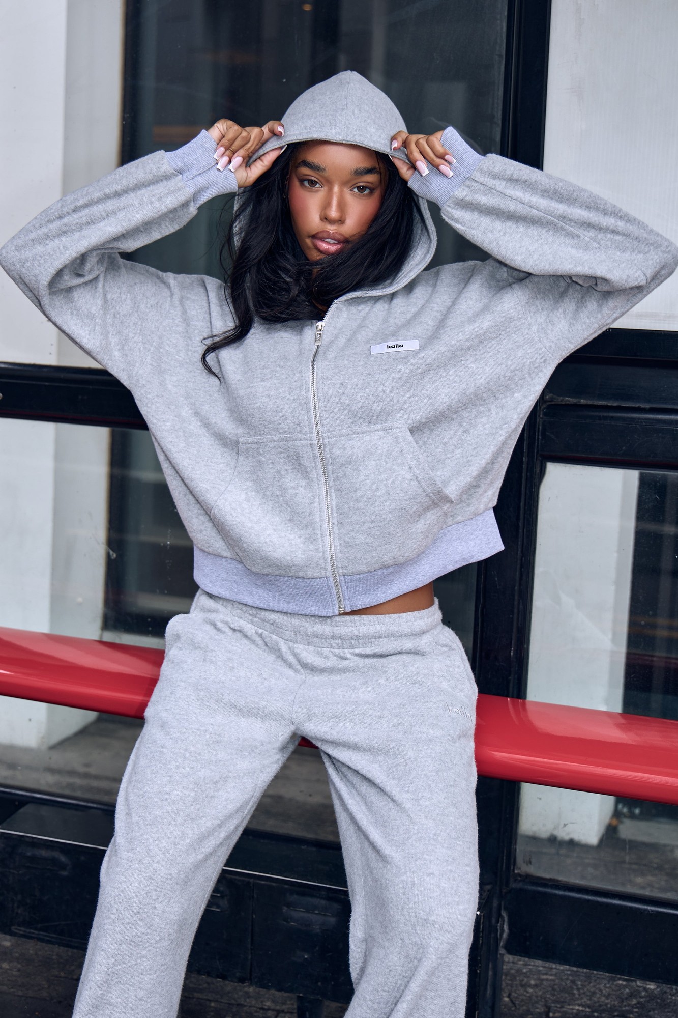 Supersoft grey marl cropped zip-through hoodie with a hood, featuring a small logo patch on the chest and ribbed cuffs, paired with matching sweatpants.