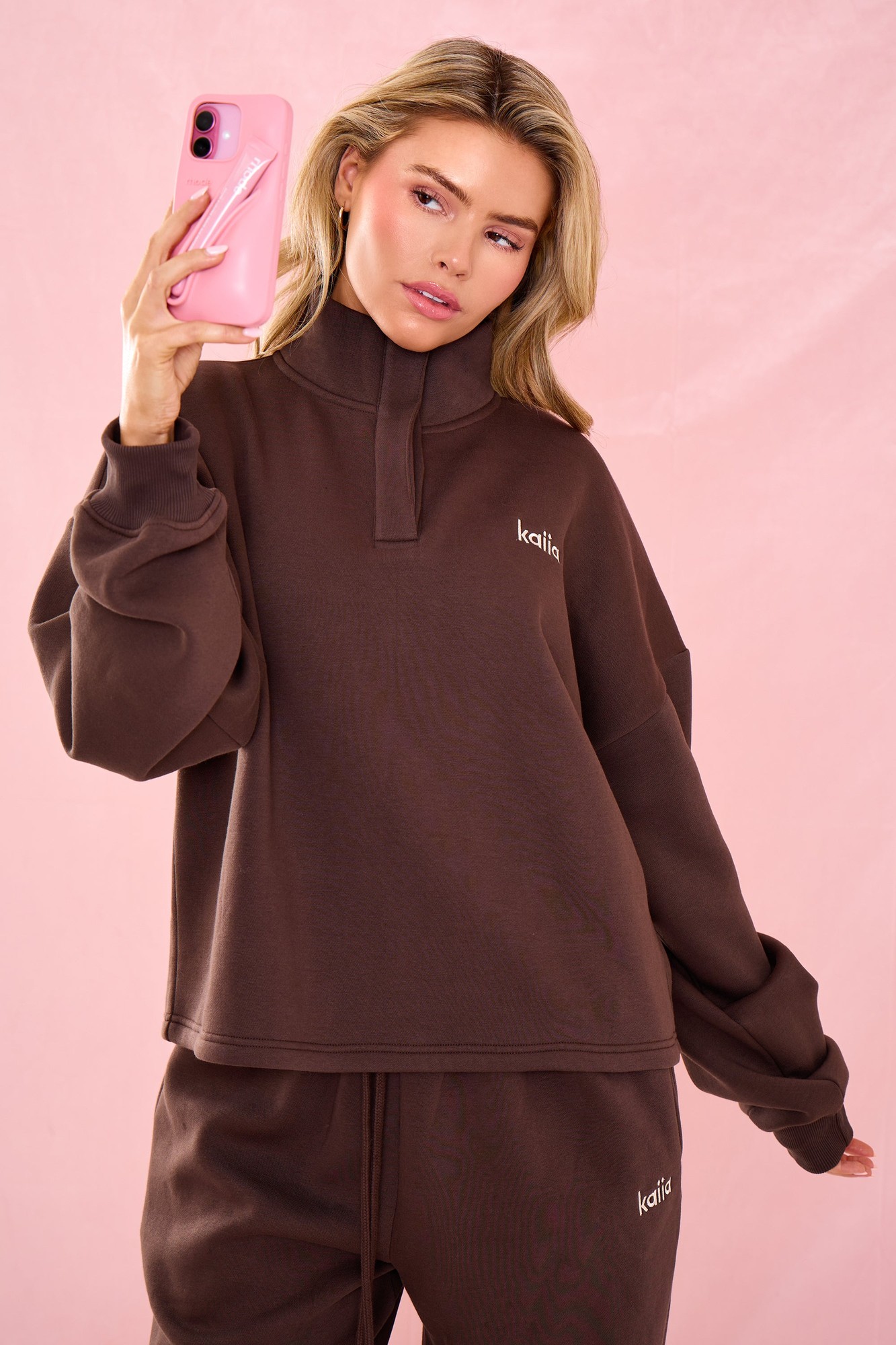 Oversized quarter neck sweatshirt in bitter chocolate, featuring a relaxed fit, soft material, and subtle branding on the chest, paired with matching bottoms.