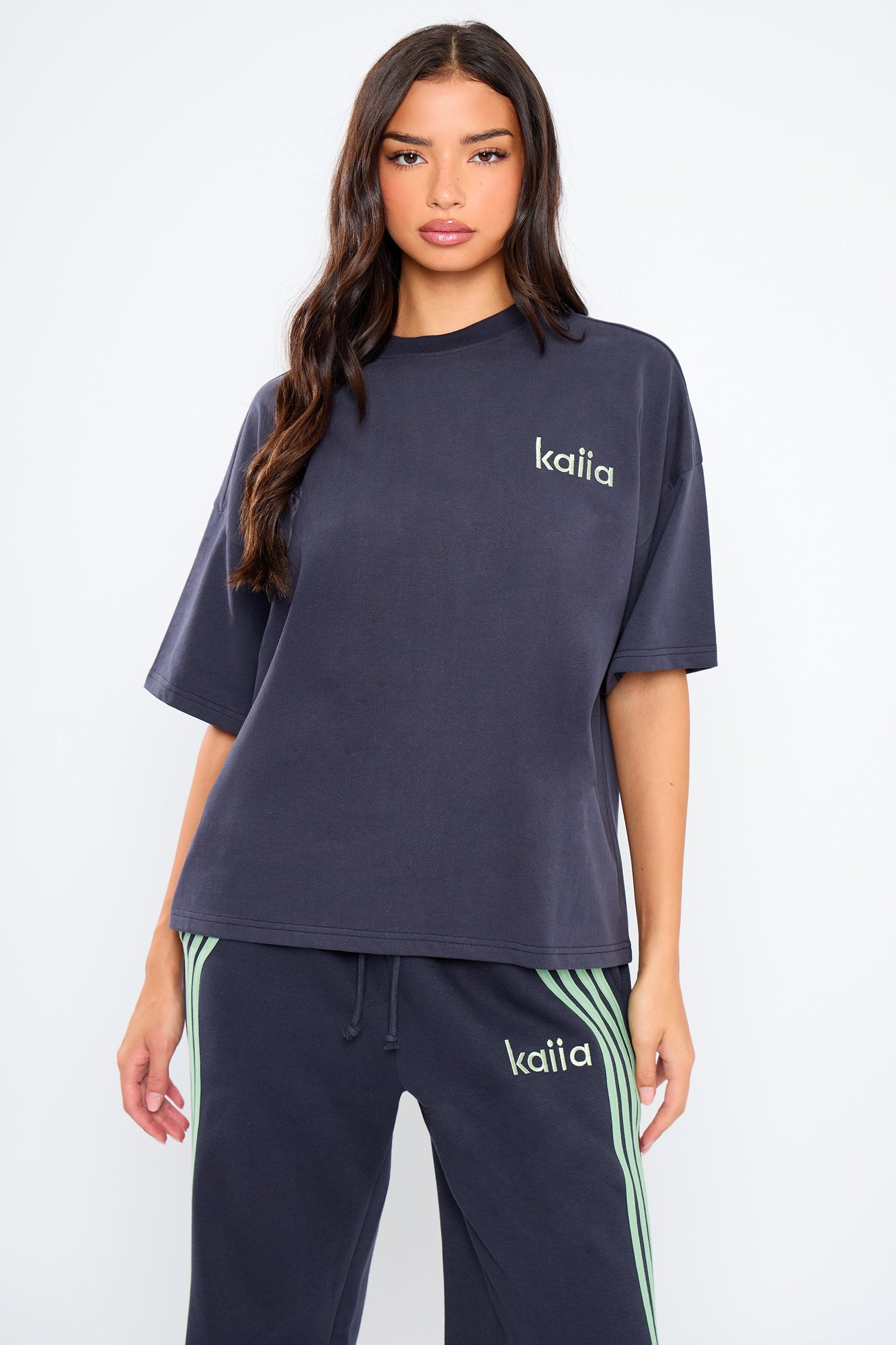 Oversized navy t-shirt with jade green "kaiia" logo, featuring a relaxed fit and soft cotton material, styled with matching joggers for a coordinated look.